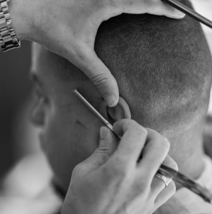 Un homme avec un dégradé chez qui se fait faire les contours avec un rasoir  chez BG Coiffure - barbier Lausanne